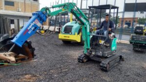 man using mini hydraulic hammer on excavator