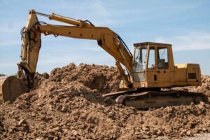 excavator scooping dirt from a mound